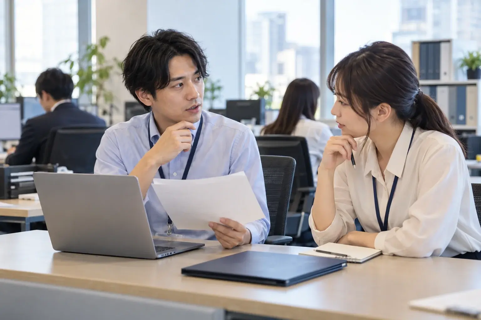 資料を入力する前に、社内の担当者へ利用条件を確認するオフィスの場面